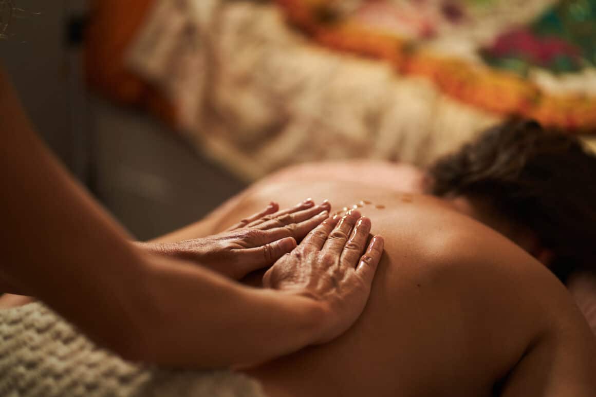 Masseur applying oil on back during relaxing massage therapy session Masaje relajante o descontracturante: cuál elegir según lo que necesita tu cuerpo