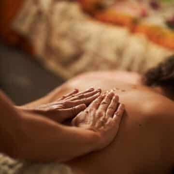 Masseur applying oil on back during relaxing massage therapy session Masaje relajante o descontracturante: cuál elegir según lo que necesita tu cuerpo
