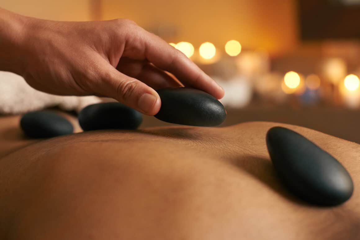 Using alternative therapy. A young woman receiving hot stone therapy at the spa Masaje con piedras calientes: qué es, beneficios y para quién está indicado