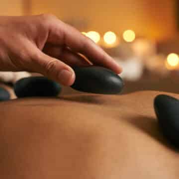 Using alternative therapy. A young woman receiving hot stone therapy at the spa Masaje con piedras calientes: qué es, beneficios y para quién está indicado