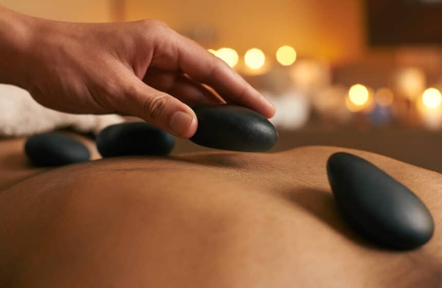Using alternative therapy. A young woman receiving hot stone therapy at the spa Masaje con piedras calientes: qué es, beneficios y para quién está indicado